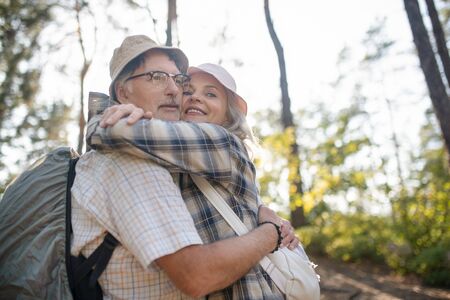 Hugging man tight. Smiling happy wife hugging her handsome man tight while walking in parkの写真素材