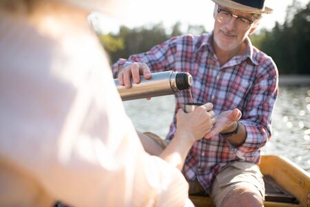 Husband pouring tea. Caring husband pouring some tea into cup for his wife while having boat tripの写真素材