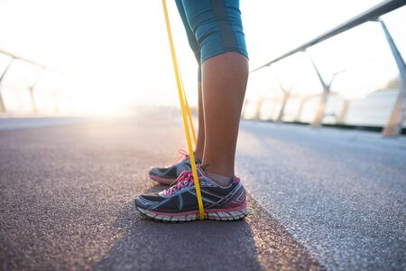 Wearing sneakers. Close up of woman wearing sneakers working out with resistance band