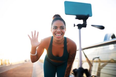 Waving to followers. Dark-skinned woman waving her followers while making sports blog