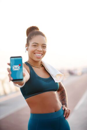 Receiving e-mail. Beaming woman feeling happy after receiving e-mail from boss after runningの写真素材