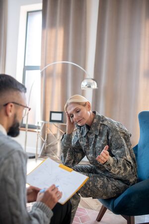 Rehabilitation time. Blonde servicewoman having military rehabilitation and psychoanalysisの写真素材