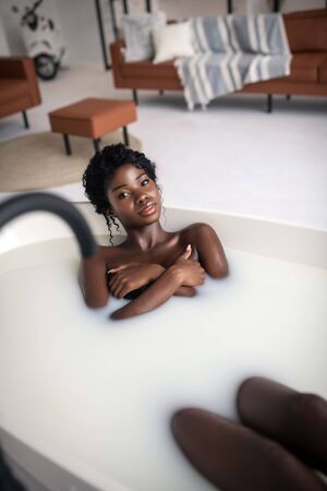 Amazing foamy bath. Dark-eyed woman having amazing foamy bath at the weekendの写真素材