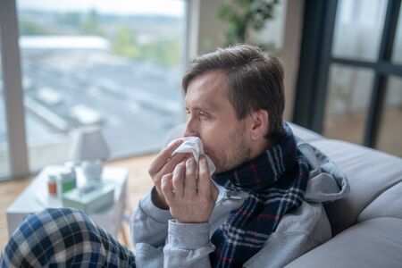 Man holding napkin. Bearded man holding napkin while having stuffy nose after catching cold