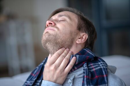 Sick and tired. Bearded mature businessman feeling sick and tired while having anginaの写真素材