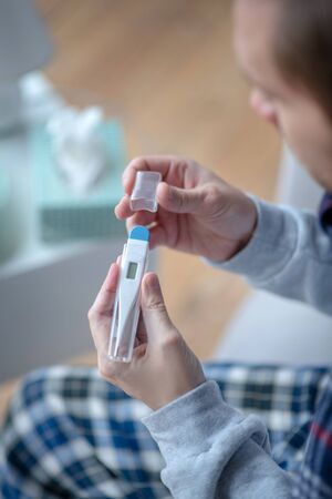 Holding thermometer. Top view of sick mature man holding thermometer while having fluの写真素材