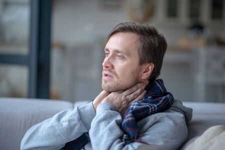 Touching neck. Blue-eyed mature man touching his neck while having tonsillitis
