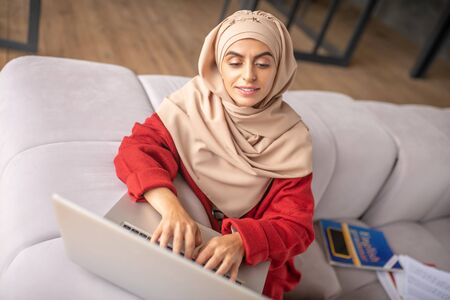 Using laptop. Portrait of pretty Muslim girl using her laptop for doing some work
