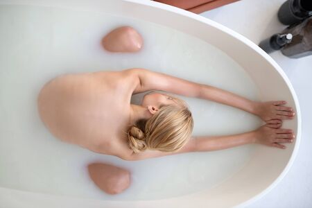Stretching back. Top view of blonde slim woman stretching her back while chilling in bath