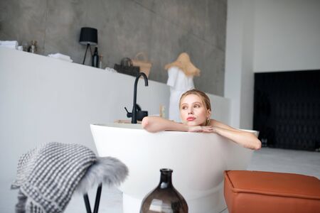 Enjoying the moment. Blonde appealing young woman enjoying the moment while having bath