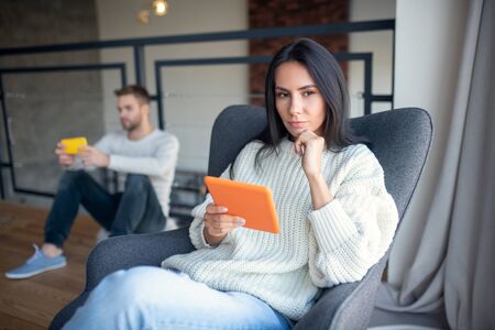 Wife feeling suspicious. Dark-eyed jealous wife feeling suspicious while husband using phone