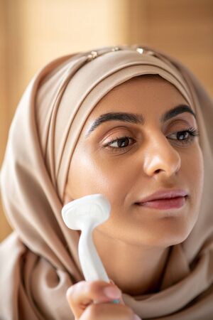 Cleansing brush. Pretty woman using silicone facial cleansing brush to get rid of makeup