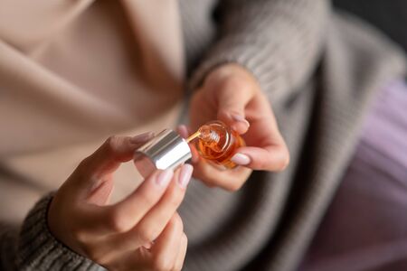 Oil for nails. Close up of girl using essential oil for nails after making manicure