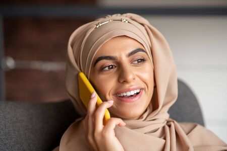 Smiling woman. Young smiling Muslim girl felling happy while talking on the phone with boyfriendの写真素材