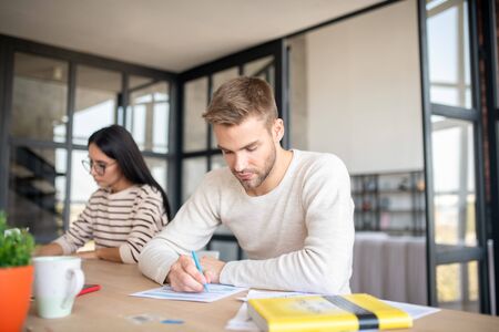 Man holding pen. Handsome bearded young man holding pen while filling tax documentsの写真素材