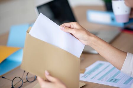 Taking letter out. Close up of woman taking letter out of envelope after going to post officeの写真素材