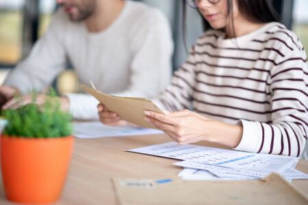 Envelopes with letters. Close up of wife wearing striped sweater holding envelopes with lettersの写真素材