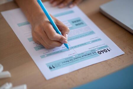 Individual tax declaration. Close up of woman filling individual tax declaration after launching businessの写真素材