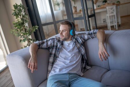 Music at home. Bearded young man chilling and listening to music at home at the weekendの写真素材