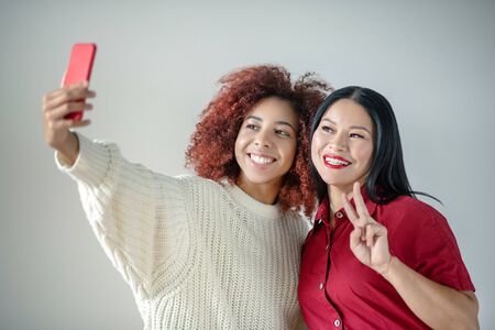 Making selfie together. Cheerful friends wearing bright clothing making selfie togetherの写真素材