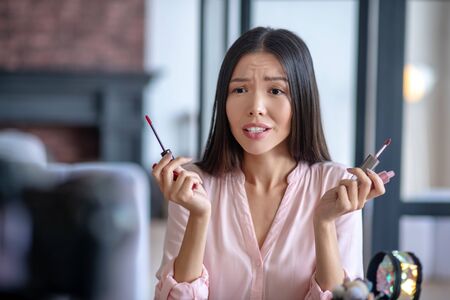 Choosing between two. Beauty blogger choosing between two lip glosses while filming beauty blogの写真素材