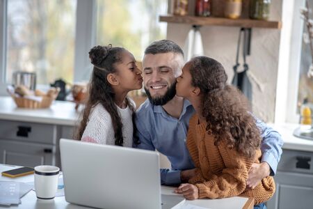 Girls kissing daddy. Cute loving girls kissing their daddy while feeling happy togetherの写真素材