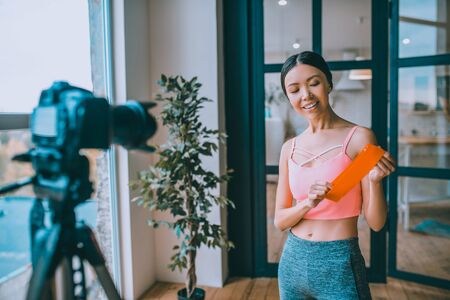 Nice resistance band. Smiling fitness blogger recommending nice resistance band while filming blogの写真素材