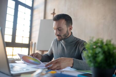 Enjoying work. Handsome interior designer enjoying work while choosing colorの写真素材