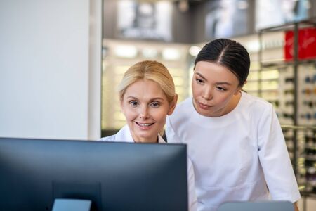 Teaching trainee. Blonde-haired experienced ophthalmologist teaching her trainee during working dayの写真素材