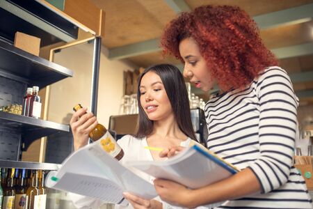 Looking at bottle. Two young entrepreneurs looking at the bottle of juice while ordering drinksの写真素材