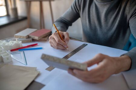 Designer holding pencil. Close up of interior designer holding pencil while making sketchesの写真素材