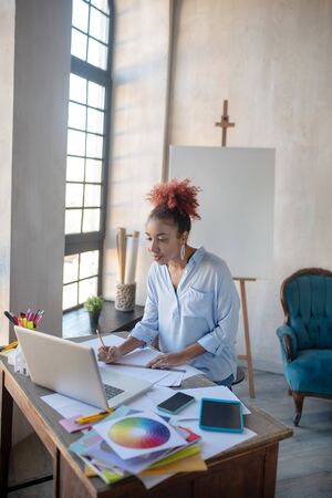 Beautiful interior designer. Curly beautiful interior designer working hard on important projectの写真素材