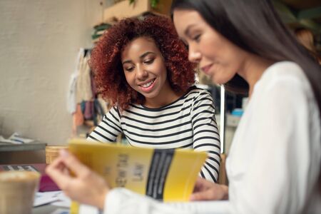 Latte and books. Top view of young businesswomen drinking latte and reading business books