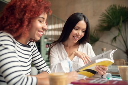 Business literature. Promising businesswomen drinking coffee and reading business literatureの写真素材