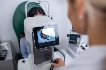 Examining businesswoman. Professional eye doctor examining eyesight of businesswoman in the morningの写真素材