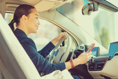 Good news. Pleased brunette woman keeping smile on her face while sitting in her car