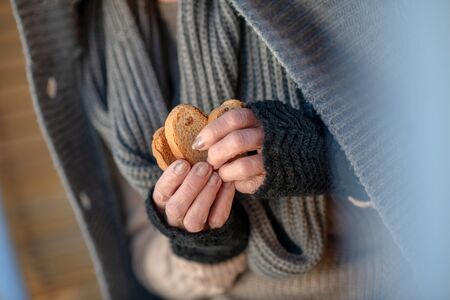 Woman with crackers. Poor homeless woman wearing scarf holding crackers while feeling so hungry