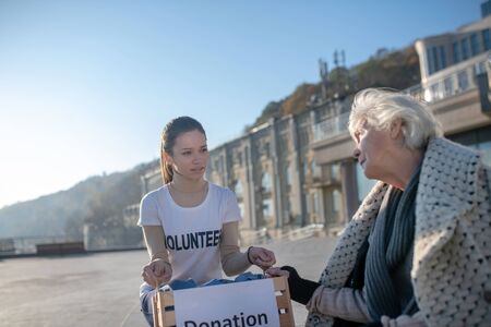 Feeling thankful. Poor homeless pensioner talking to kind young volunteer feeling thankfulの写真素材