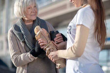 Pensioner smiling. Homeless poor hungry pensioner smiling while seeing volunteer with bread and tea