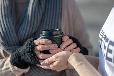 Cup of tea. Close up of kind supporting helpful volunteer giving cup of hot tea to poor womanの写真素材