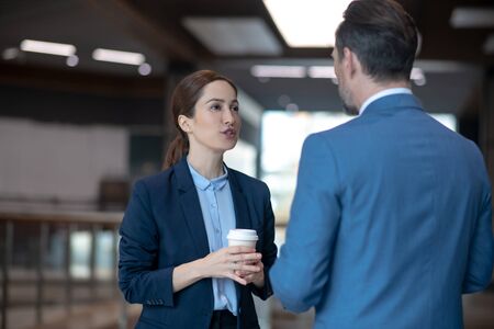 Business lady talking. Beautiful business lady talking to her business partner while drinking morning coffeeの写真素材