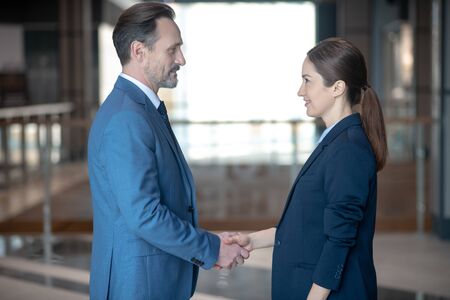 Shaking hands. Successful businessman and businesswoman shaking their hands before serious negotiationの写真素材
