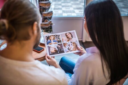 Wedding album. Close up of engaged couple choosing cover for wedding album together