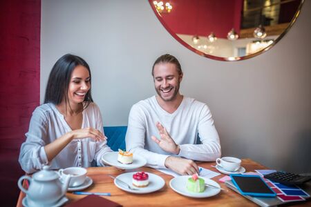 Couple laughing. Cheerful couple of businessmen laughing while trying desserts for their new bakeryの写真素材