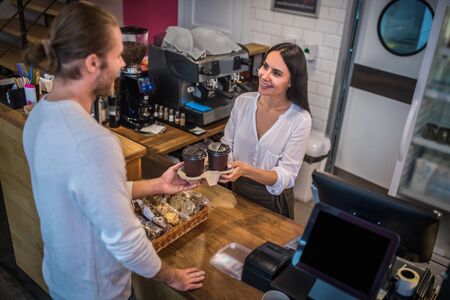 Smiling beautiful barista. Smiling beautiful barista giving takeaway coffee to customer in the...