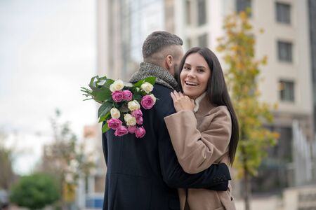 Romantic present. Joyful young woman smiling while holding a beautiful flower bouquetの写真素材