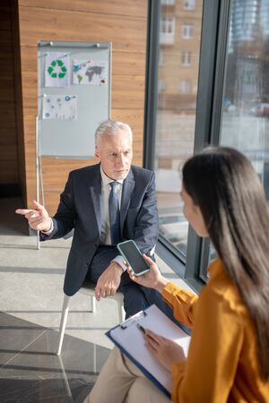 Business talk. Asian female reporter with long hair having a talk with a mature businessmanの写真素材