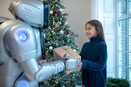 Good friend. Robot giving a christmas present to a smiling girlの写真素材