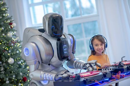 Young dj. Cute girl in earphones trying herself as dj sitting at djs tableの写真素材