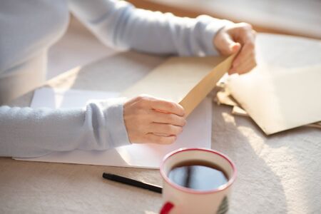 Important letters. Young cute woman in grey homewesar reading lettersの写真素材